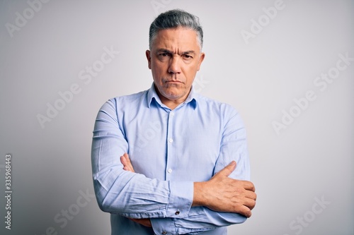 Middle age handsome grey-haired business man wearing elegant shirt over white background skeptic and nervous, disapproving expression on face with crossed arms. Negative person.