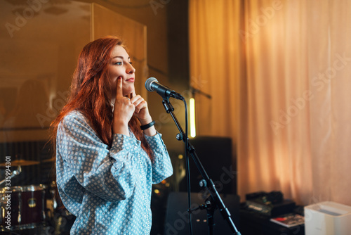 girl does exercises with lips at chants in vocal lesson near the microphone