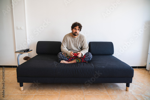 Young bearded man sitting on a couch playing console