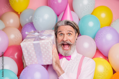 Close-up portrait of his he nice attractive cheerful cheery funky grey-haired mature man having fun holding in hands giftbox isolated over pink pastel color background