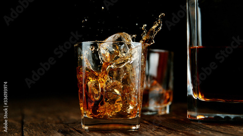 Splashing whiskey from glass with ice cubes inside