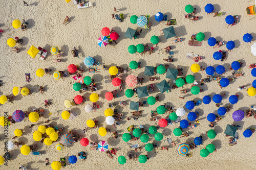 Drone shot of beach goers under umbrellas on the beach