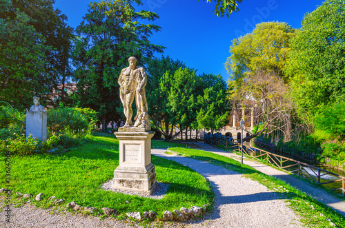 Farnese Hercules (Ercole Farnese) ancient statue of Hercules in Salvi gardens park with green trees and lawn, Valmarana Lodge building, historical city centre of Vicenza city, Veneto region, Italy