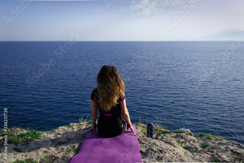 Beautiful young happy lonely girl watching the Mediterranean sea and relaxing