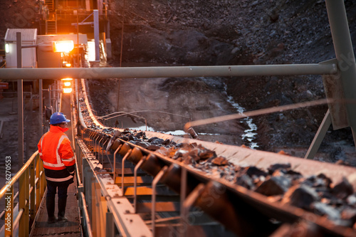 Nyngan Australia June 20th 2012 : Shallow depth of field image of a miner inspecting ore rocks on a conveyor in NSW Australia