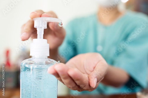 Woman wearing a coronavirus (covid-19) protective prevention mask. She uses a handwashing gel to wash her hands sanitizer to avoid contamination.