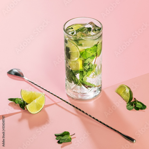 mojito cocktail on a pink background with mint leaves and lime