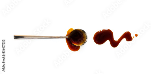 Spoon with teriyaki and soy sauce splash isolated on white background, top view. Close-up seasoning and dip