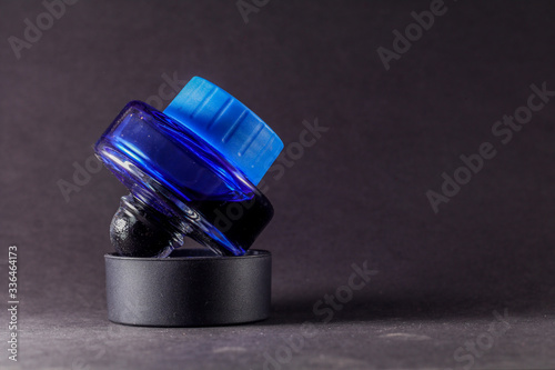 a view of closed blue ink bottle against black background