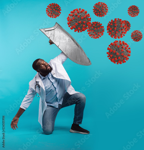 Doctor with metal shield defending from covid 19 disease on cyan background