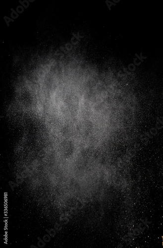 White dust is scattered by an explosion on a black background, an abstract cluster of white particles, a snowstorm on a black background