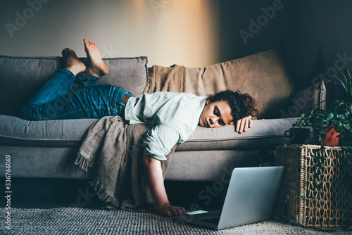 Bored woman in self isolation laying on the sofa. Woman in quarantine for coronavirus working from home.