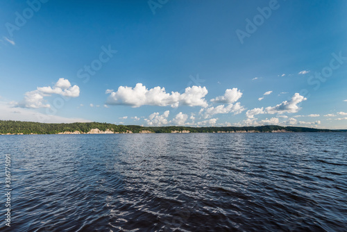 Panorama of calm lake, Kama river blue sky with clouds reflected in the water.