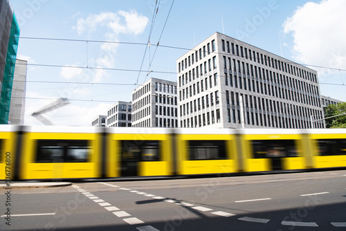 yellow tram rides quickly against the background of white houses in Berlin
