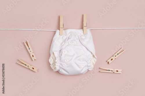 Reusable cloth baby diapers drying on a clothes line. Eco friendly cloth nappies on a pink background. Sustainable lifestyle. Zero waste concept.