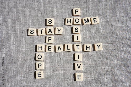 Word game with crossword grids showing various words - stay, home, hope, healthy, safe, and positive - isolated on gray cotton background. Stay home and be positive concept.