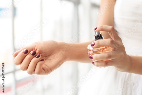 Beautiful young bride with perfume at home, closeup