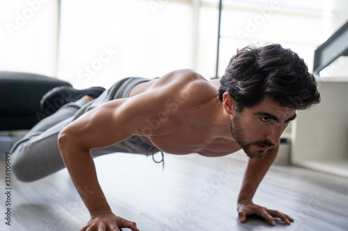 Young adult male working out at home doing push ups.