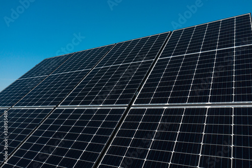 Background of photovoltaic modules for renewable energy. Huge solar panels with clear blue sky.