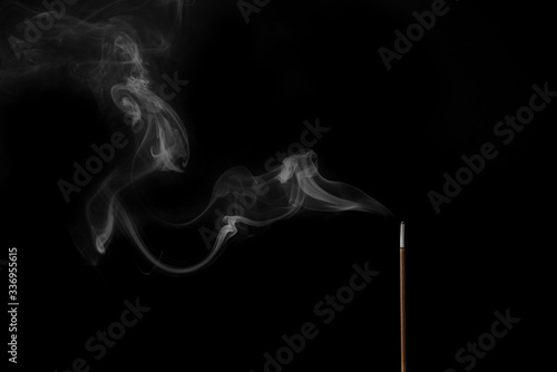 Incense stick smokes on a black background