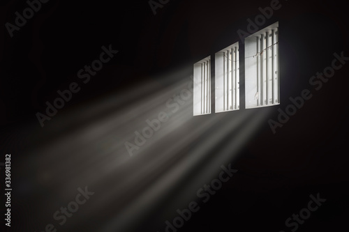 Beams of light through a barred prison cell window