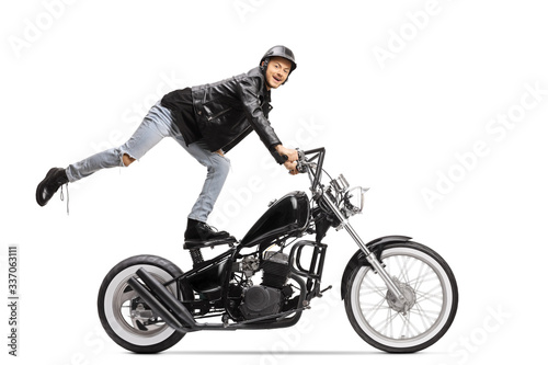 Young biker standing on the seat and riding a motorbike