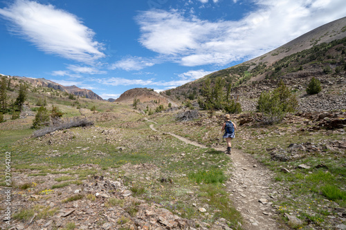 Woman hiker walks along the dirt trail in the 20 Lakes Basin hike in California Eastern Sierra Nevada mountains in the summer. Concept for explore, exploring