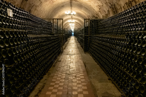 A long antique cellar with lots of aged wine bottles. Sparkling wine production
