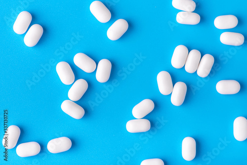 White dragees lie in a pile on a blue background. Close-up, macro photography. Lots of white mints