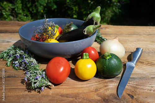 Un saladier sur une table en bois avec à l’intérieur comme à l’extérieur des légumes de toutes les couleurs 