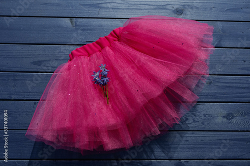 Pink tutu skirt for girl on blue wooden background.