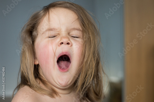 Emotion. Girl 4 years yawns. Portrait. Close-up. Gray background. Copyspace.