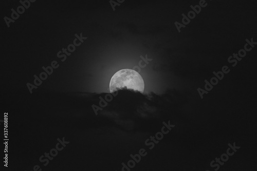 Super moon in a black sky with clouds