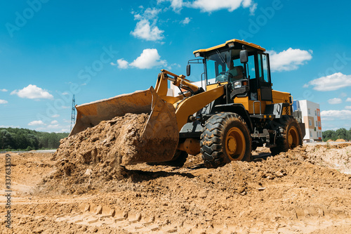 large yellow tractor at a construction site a bulldozer cleans the site with a bucket