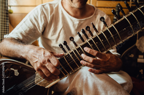 Close up photo of hands of an Indian musician playing a sitar