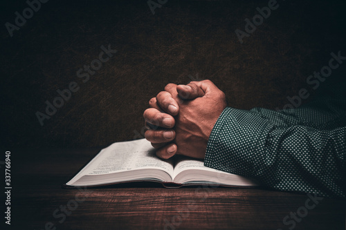 Hands of a man praying over an open bible