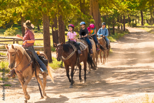 Family taking a horseback riding lesson in the woods in the Rocky Mountains, Colorado, USA, in summer