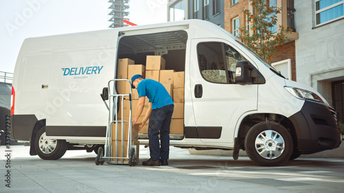 Courier Takes out Cardboard Box Package From Opened Delivery Van Side Door. Professional Courier / Loader helping you Move, Delivering Your Purchased Items Efficiently