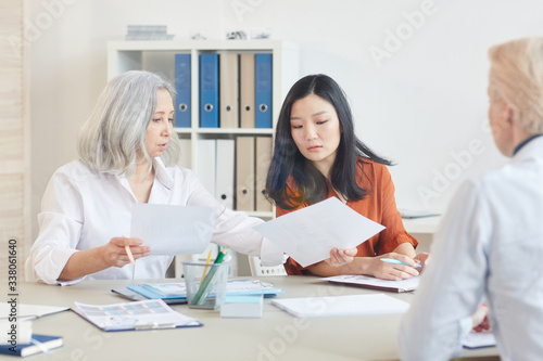 Portrait of successful senior businesswoman talking to younger colleagues during meeting in conference room, copy space