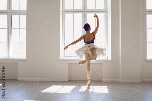 Ballerina. Young graceful ballet dancer is rehearsing a performance in a white studio with windows.