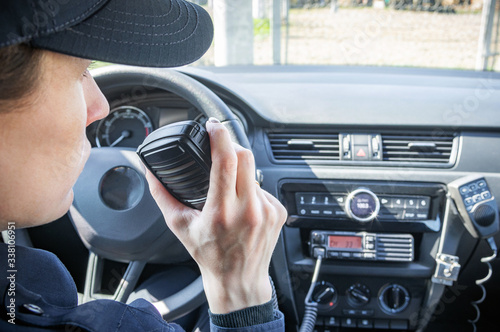 Microphone of a radio or walkie-talkie in the hand of a female police officer in her patrol police car. 