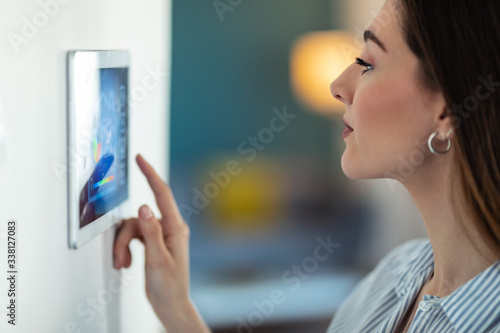 Pretty young woman using the home automation system on digital tablet to regulate the temperature.