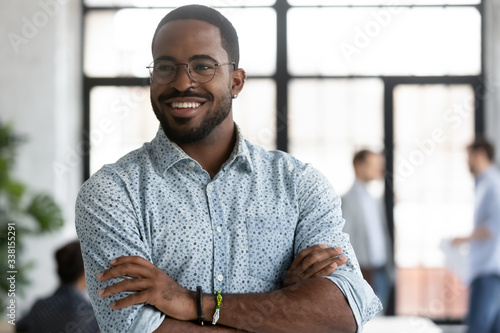 Happy motivated African American businessman in glasses look away thinking or pondering, smiling biracial male employee lost in thoughts consider career opportunities, business vision concept