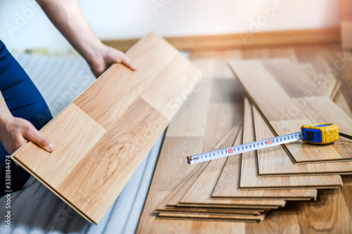 Worker hands installing timber laminate floor in modern house. Wooden floors renovation