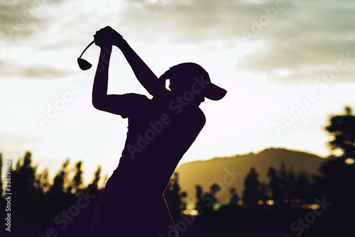 Silhouette of young professional female golf player hit sweeping and keep golf course doing golf swing,she does exercise for relax time