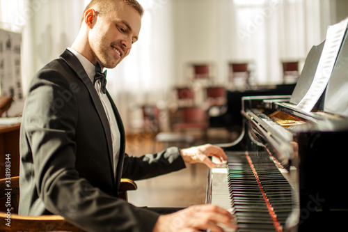 professional caucasian man musician gracefully play piano on a stage, talented pianist in formal elegant suit perform music