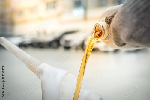 Pouring engine oil into the engine room., Gold oil during car oil change in the repair shop or service center.,interior car-care center
