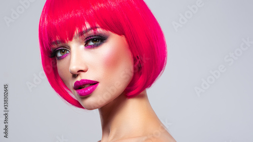 Caucasian fashion model with bob hairstyle colored in pink. Female Eyes with vivid makeup.