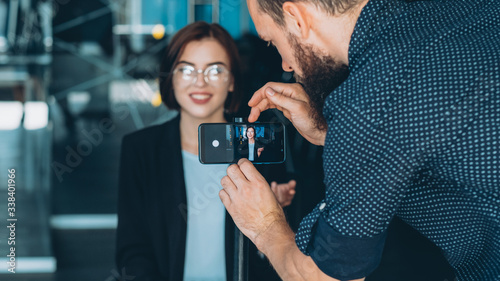 Corporate vlog. Successful career. Male assistant recording smart business woman interview on phone.