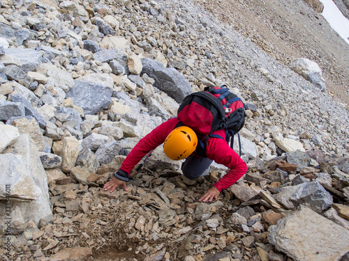 a man scrambling up a steep mountain slope covered with scree